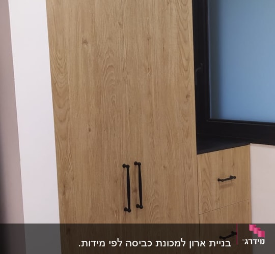 ארון עץ עם ידיות שחורות ליד חלון
